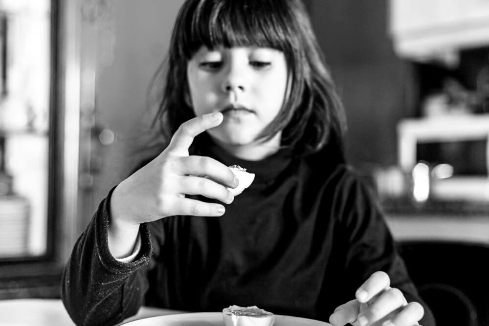Girls contemplates food item with skepticism
