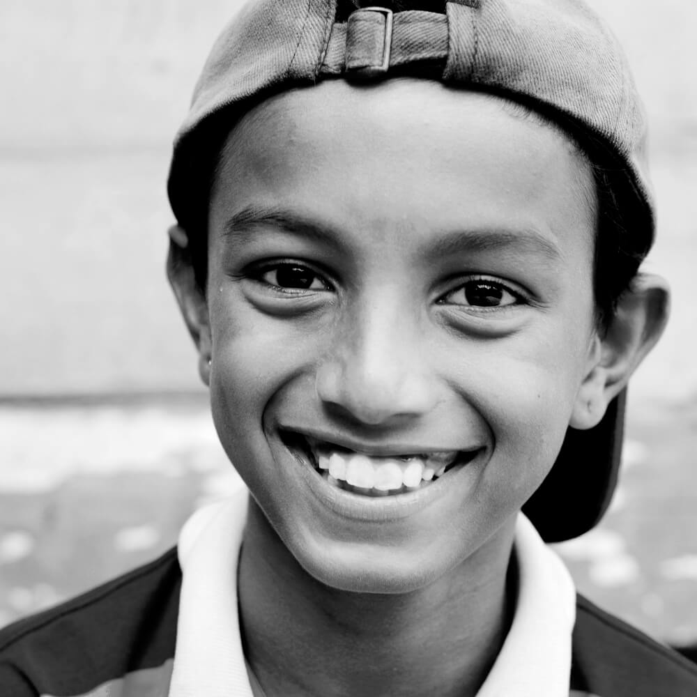 boy with cap smiling at camera
